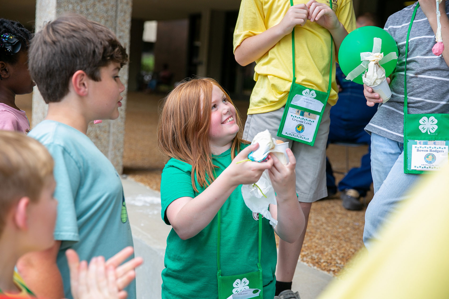 A girl smiling and holding a paper towel while a little boy looks on.