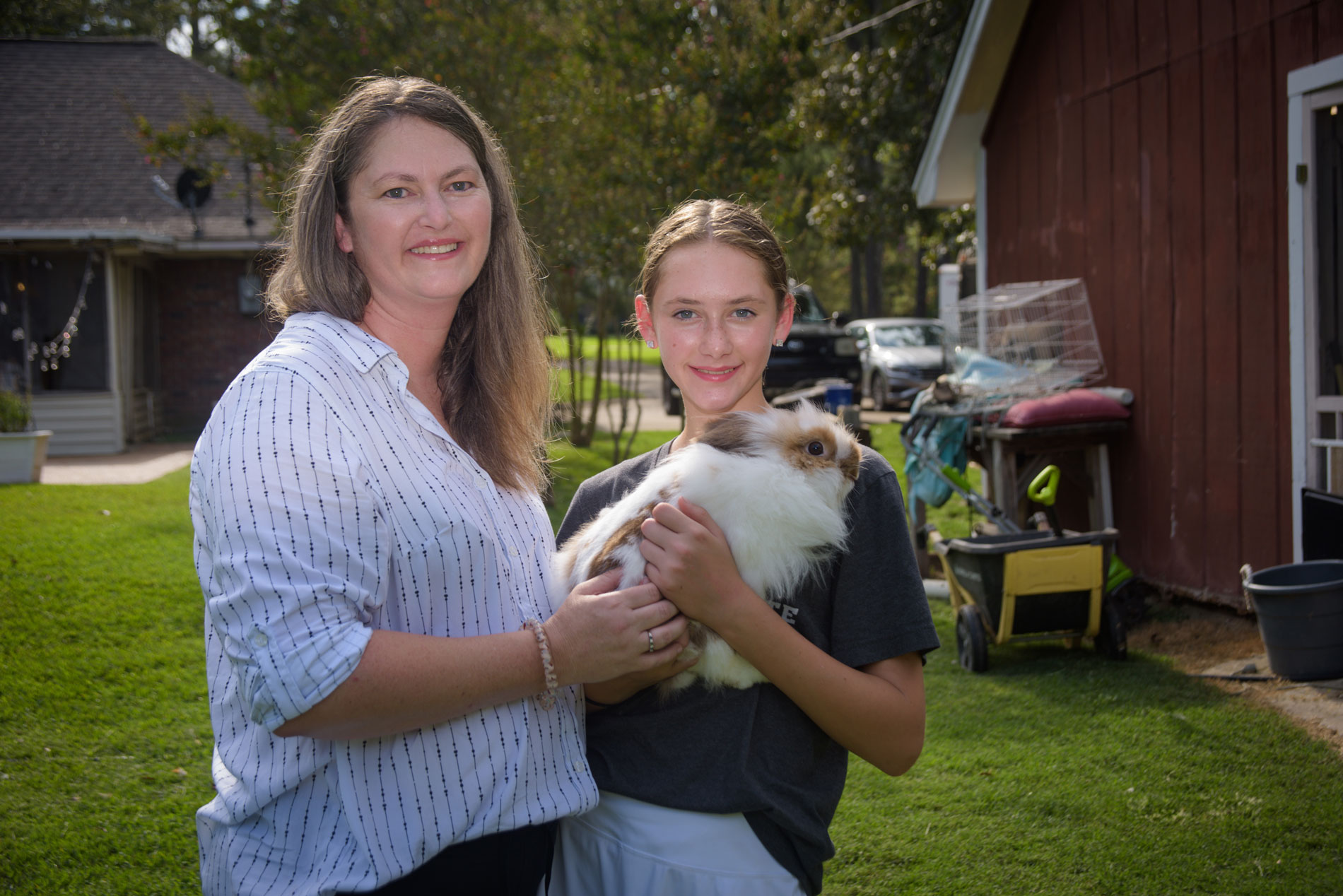 A girl holding a rabbit with a woman on her left who’s also touching the rabbit.