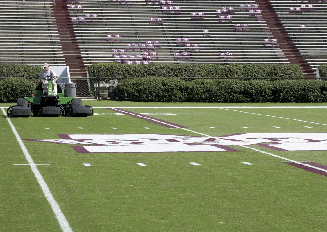 A field manager cuts the grass on the Mississippi State football field. 