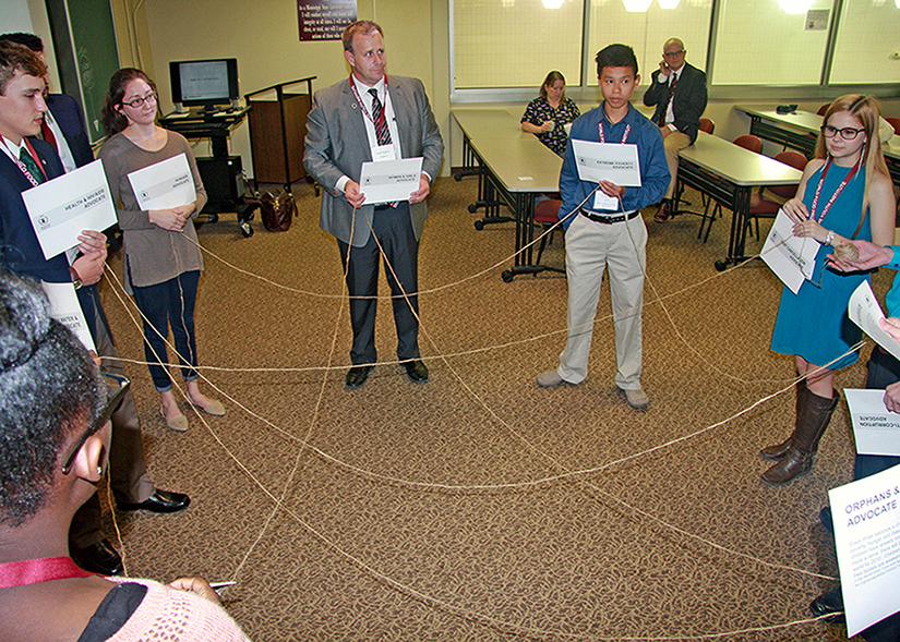 group of participants in a circle connected by string.