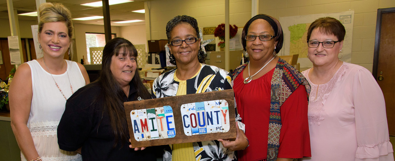 • Five women standing and smiling inside an office