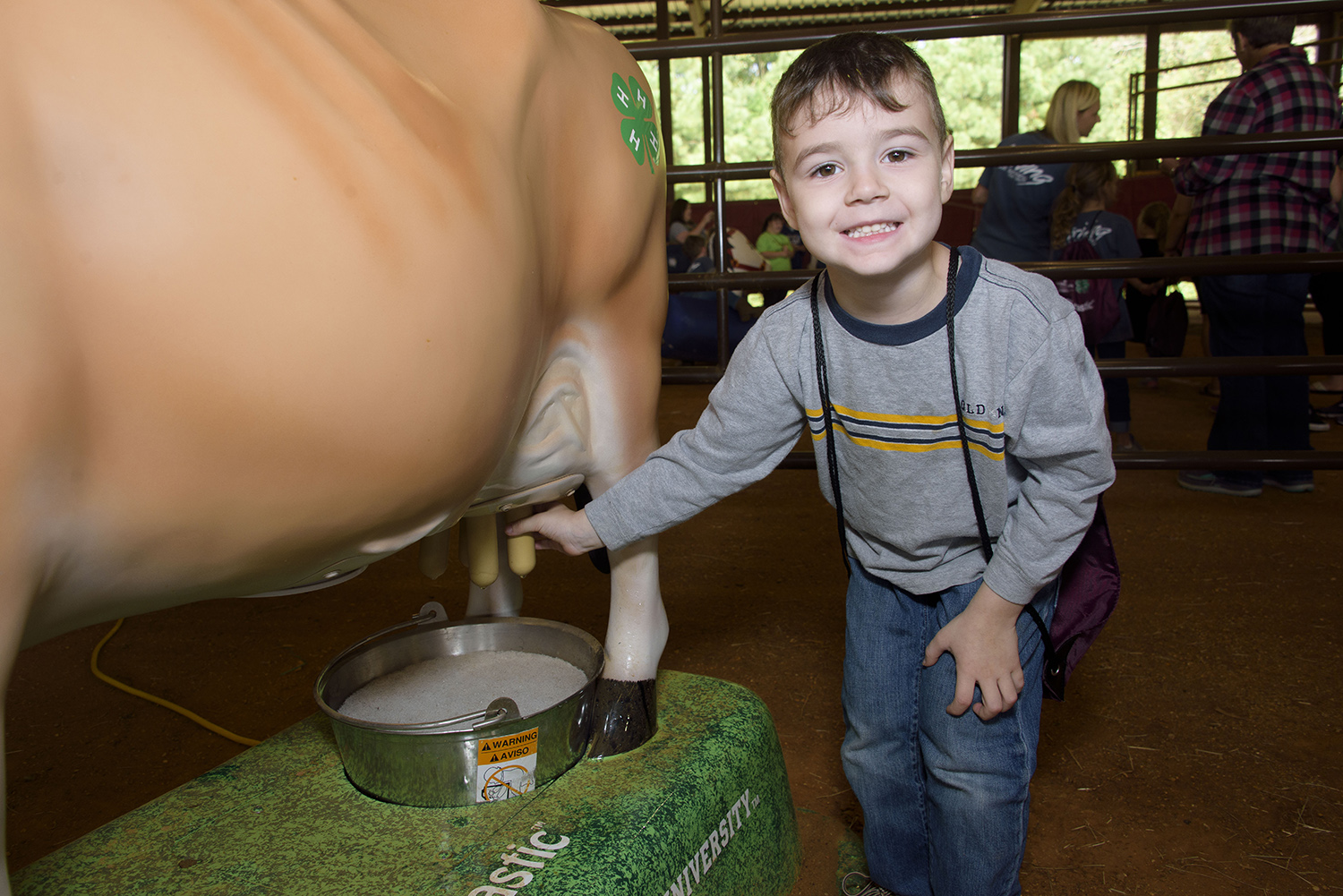 A young child squeezes the mechanical cow’s teat that simulates an udder to demonstrate the milking process.