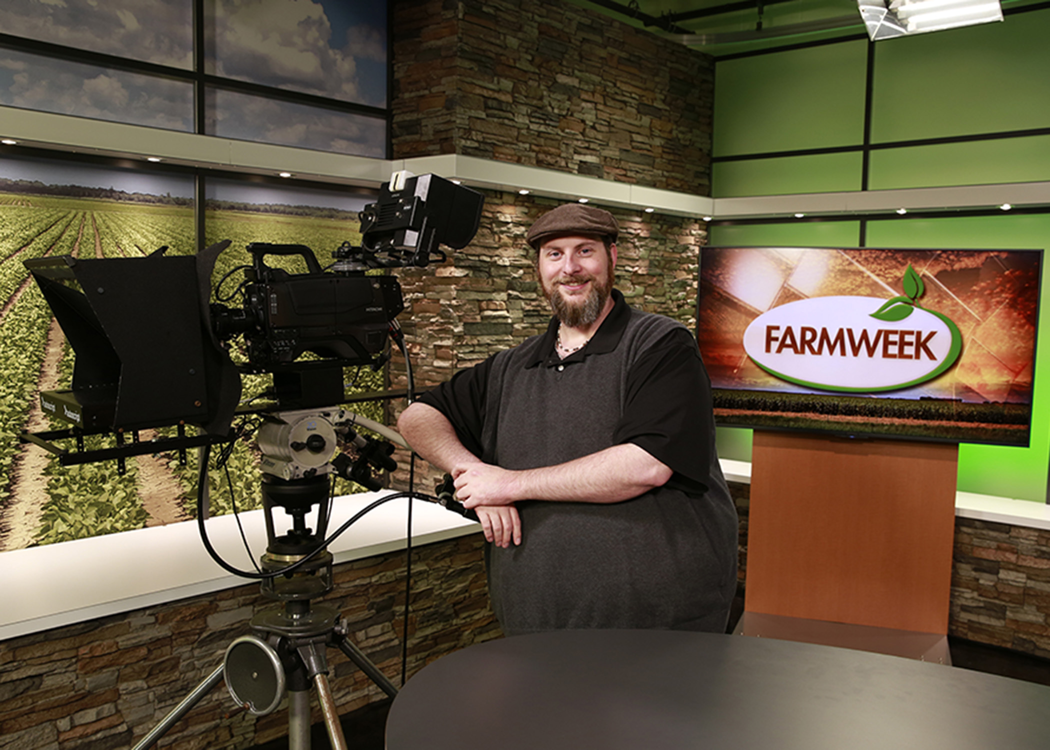 Bearded man in hat on Farmweek TV studio set.
