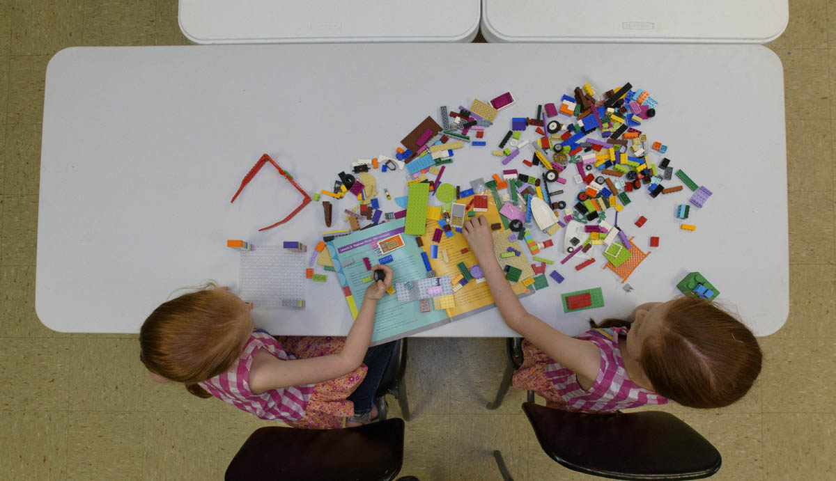 Overhead shot of two young girls with red hair working with Legos.