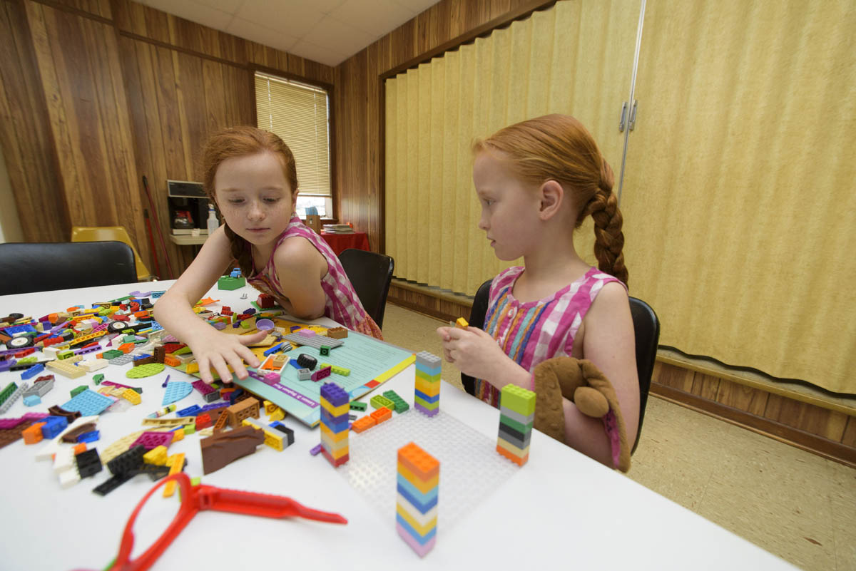 Two young girls with red hair working with Legos. 