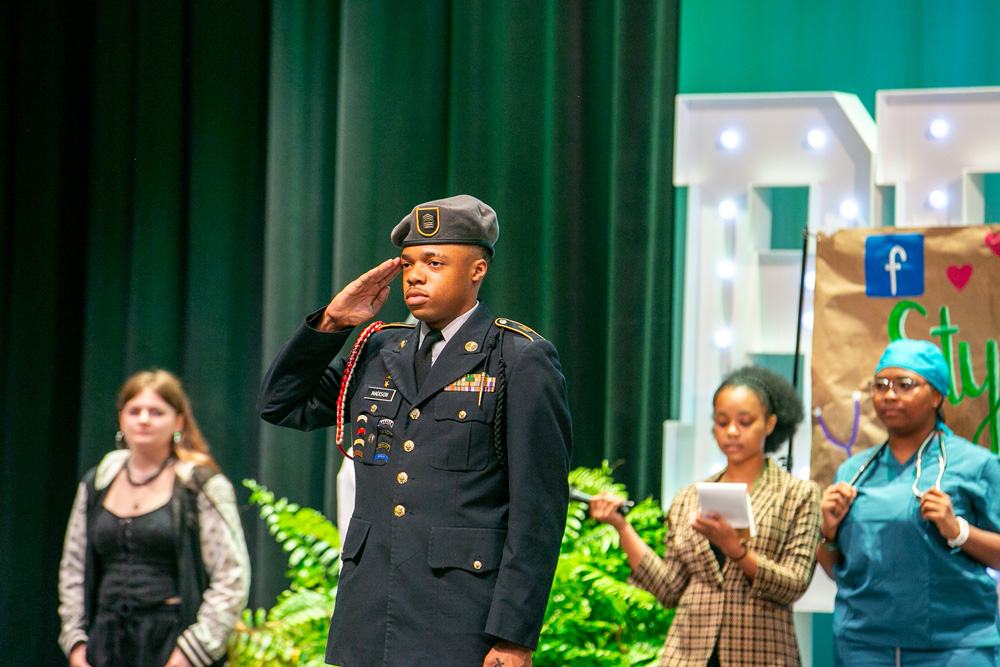 A teen wearing a military uniform, saluting.