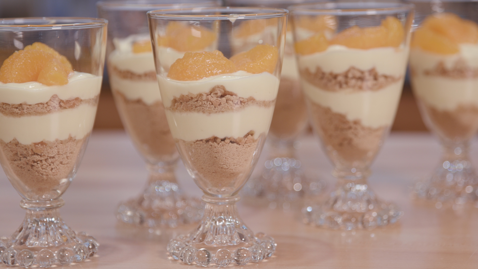 Clear glass parfait cups with lemon pudding layered with graham cracker crumbs topped with manadarin orange slices