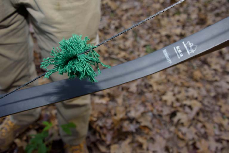 Completed yarn bow string silencer is shown attached to a bow's string. The silencer is made of green yarn.