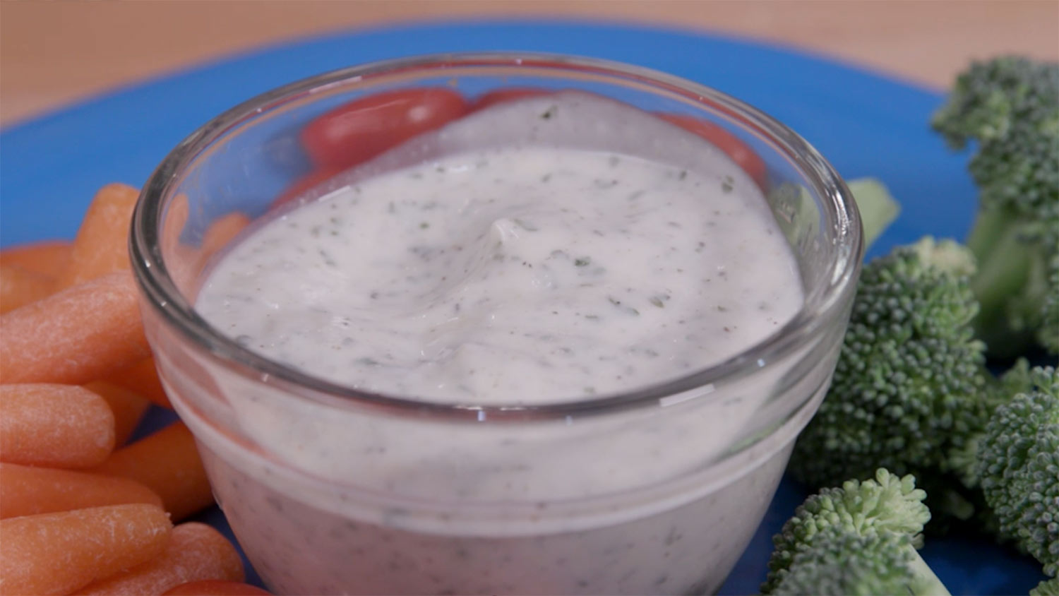 Ranch dressing in a clear glass bowl.