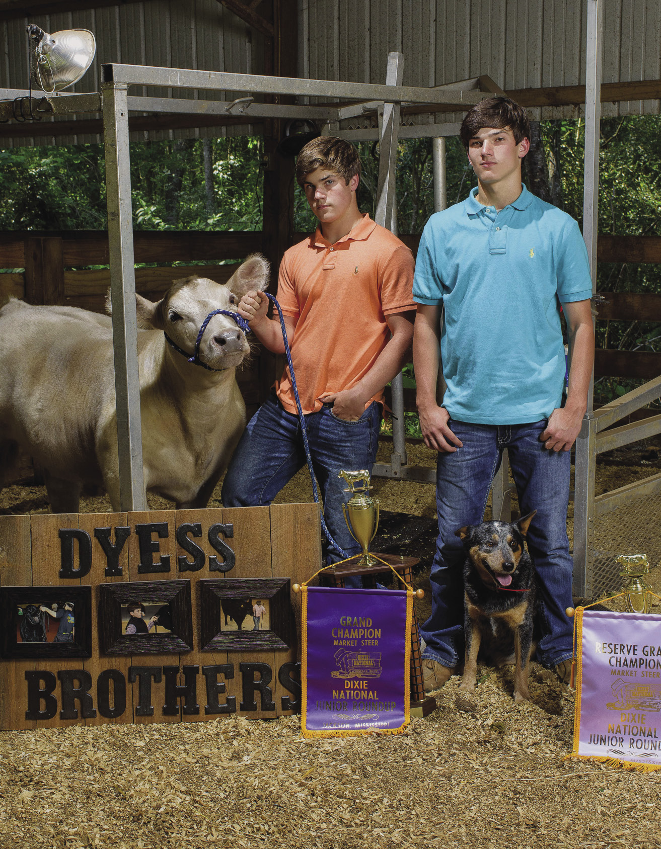 2 young men with a calf and a dog and Dixie National trophies.