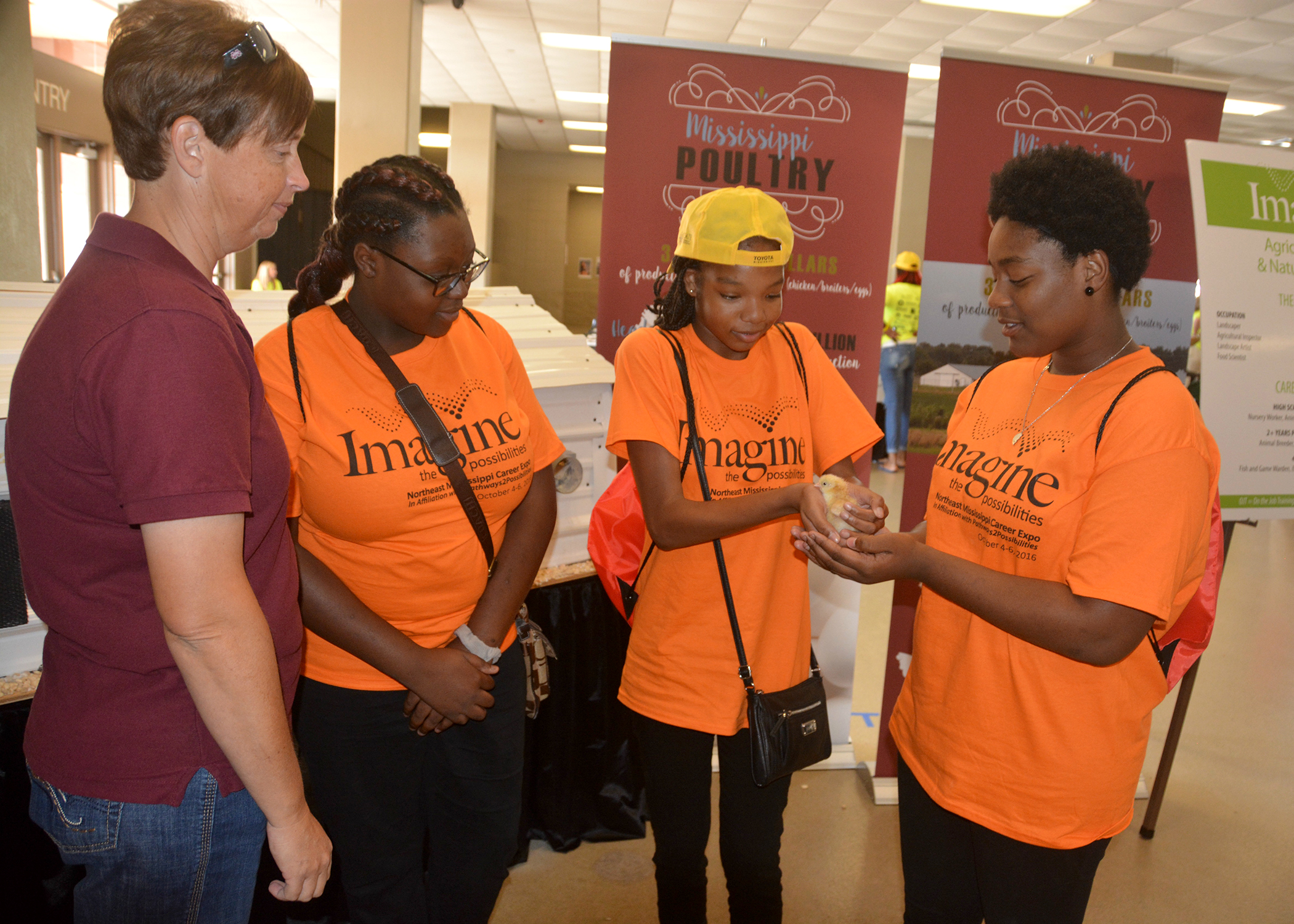 Union County Extension agent Gina Wills, left, watches as India Hamilton, Kaitlyn McGee and Ja’vonne Rich examine a newly hatched chick at the poultry booth on Oct. 5, 2016, at a career expo for eighth-graders in Tupelo, Mississippi. The three students, all from Armstrong Middle School in Starkville, Mississippi, were among 7,000 students taking part in the event sponsored by the CREATE Foundation Toyota Wellspring Education Fund and many other individuals, companies and civic organizations. (Photo by MSU Extension Service/Linda Breazeale)