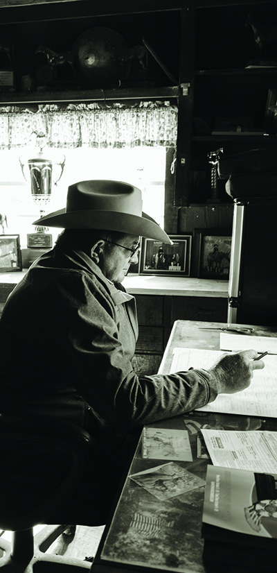 A man in cowboy hat sits at desk.