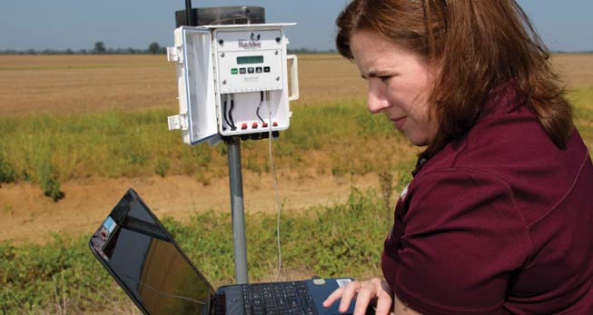 short sleeve maroon shirt, standing in field with equipment and laptop
