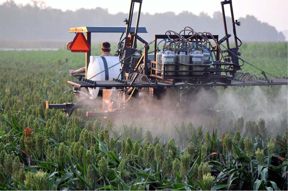 An image of a farmer applying pesticides using proper calibration of pesticide application equipment.