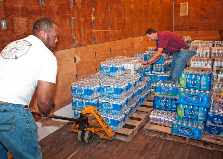 2 people loading supplies in a truck.