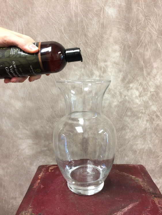 Bottle of glycerin pourin contents into glass vase.