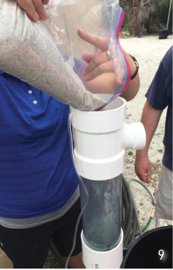 A person pours sand from a large plastic bag into a density separator.