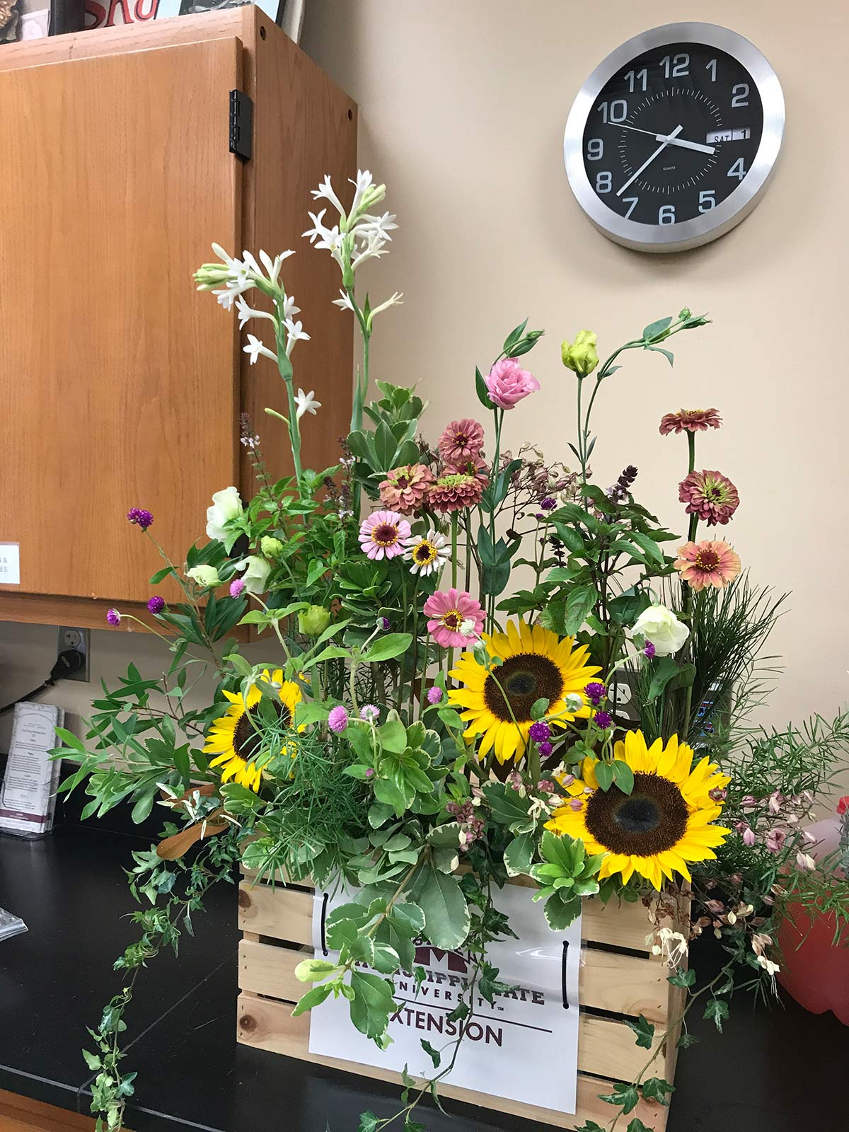 A floral arrangement with zinnias, sunflowers, and other plants.