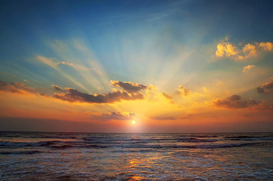 A sunset over waves on the ocean.