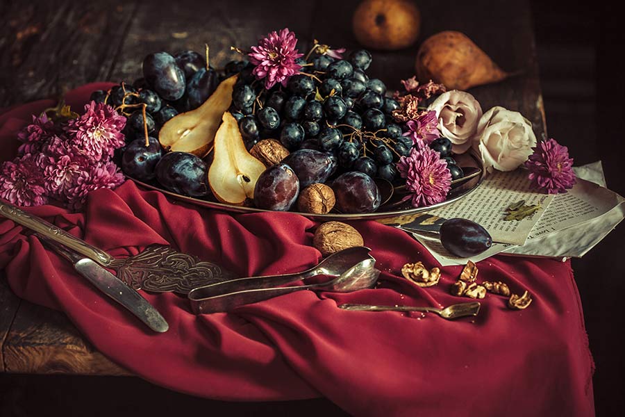 A very colorful arrangement of fruit on a red tablecloth.