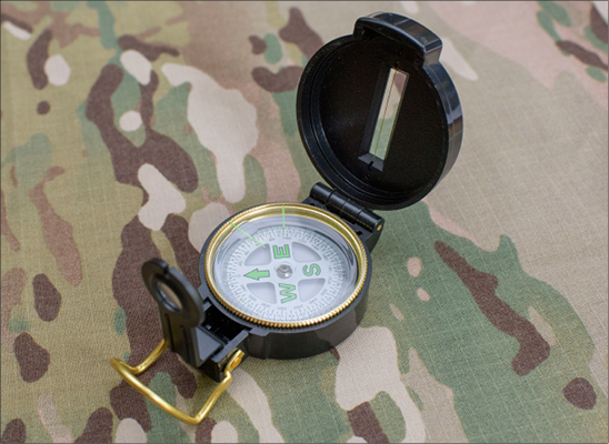 An open compass on a camouflage background.