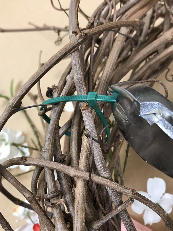 Wire cutters cutting green zip-tie.