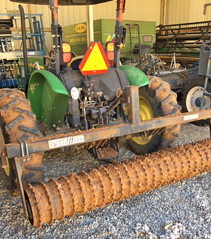 A wide, round piece of equipment attached to the back of a tractor.