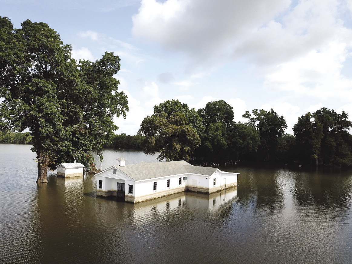 A white church building is surrounded by flood water.
