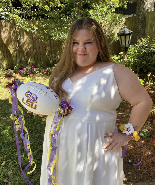 A young woman holds a decorative football.
