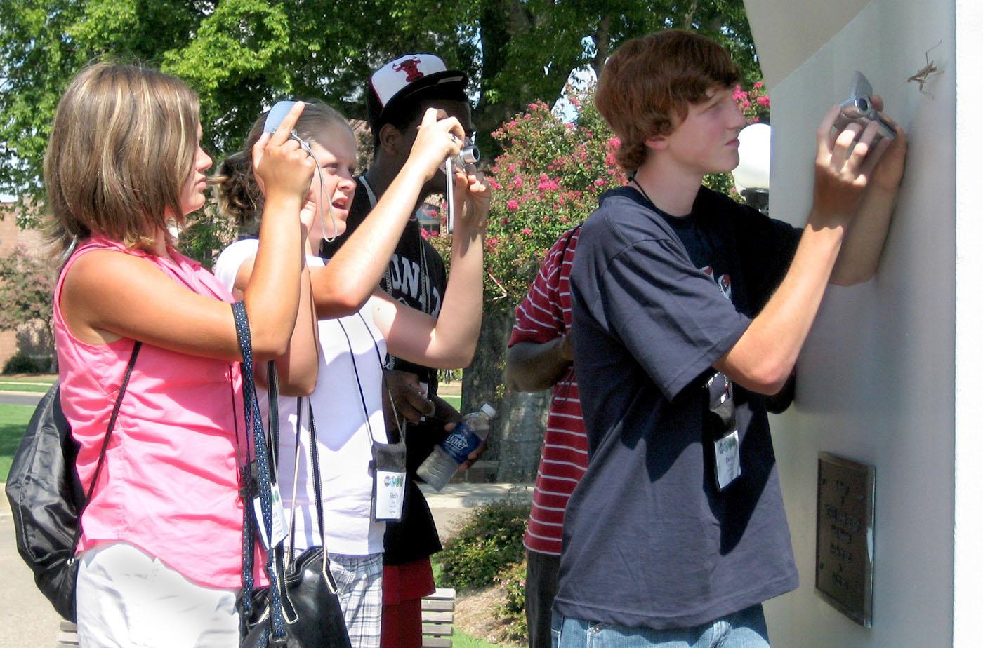4-H Technology Conference participants, from left, Tara Roberts and Shelly Guy, both of George County, and Devin Doole of Marshall County focus their cameras on a praying mantis during a photo safari. They were taking part in the digital photography track during the three-day camp held at Mississippi State University. (Photo by Jim Lytle/Mississippi State University Ag Communications)