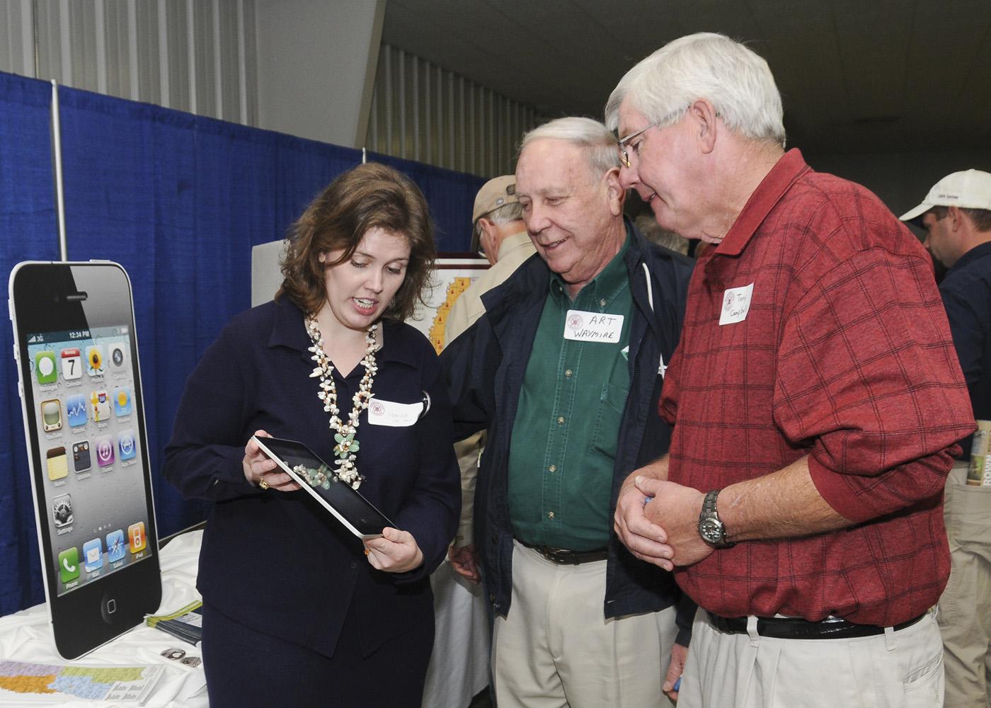 Mariah Smith (left), Extension computer applications instructor, discusses the iPad and its use in agricultural production with Art Waymire (center), a tree farmer from Marshall County, and Tony Campbell, a cotton and soybean farmer from Itawamba County. (Photo by Scott Corey)