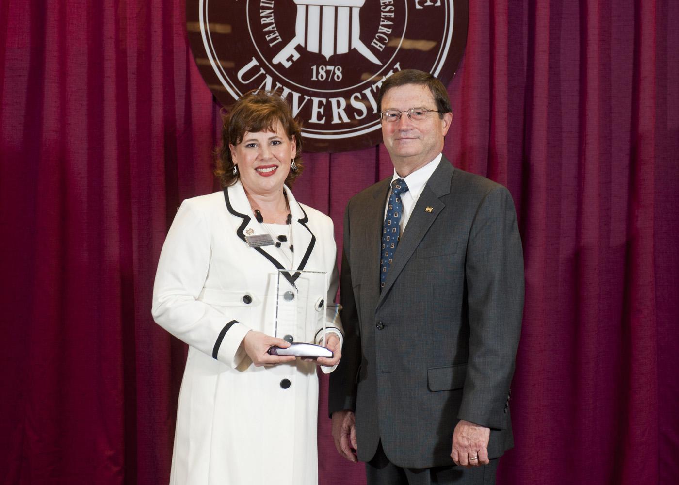 Deputy State Veterinarian and Public Health Veterinarian Dr. Brigid Elchos, left, accepts her alumnus of the year award from Dr. Kent Hoblet, dean of Mississippi State University College of Veterinary Medicine. Elchos received the honor because of her outstanding achievements and leadership. (Photo by MSU University Relations/Megan Bean)