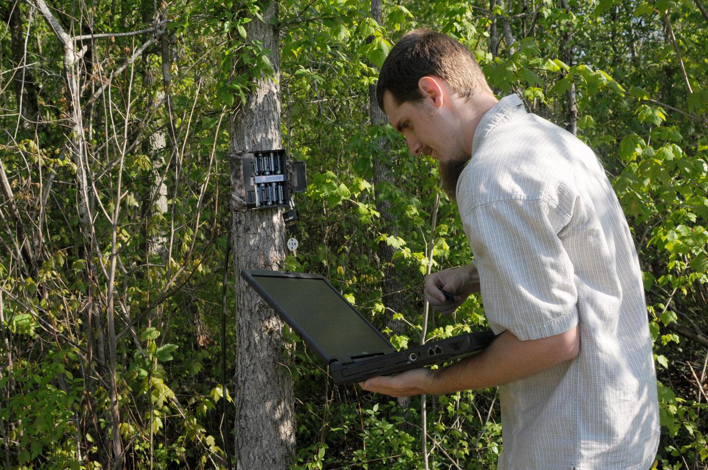 Edward Entsminger, wildlife and fisheries science graduate student, checks trail cameras to monitor wildlife presence and spreads native wildflower seeds. (Photo by Kat Lawrence)