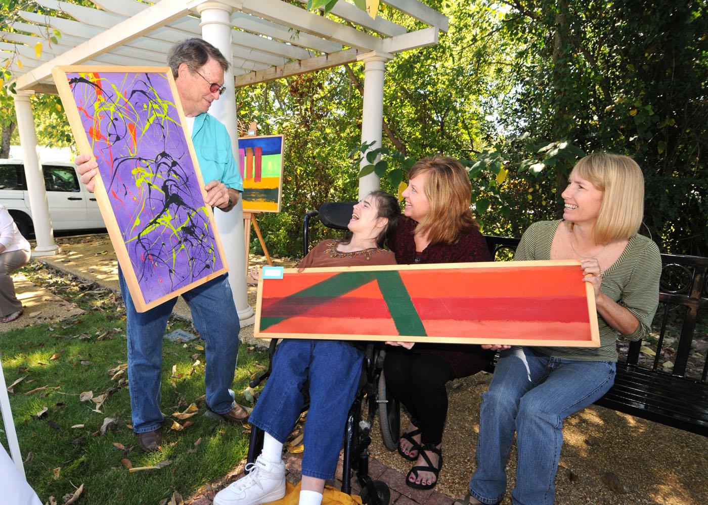 Chickasaw County Master Gardener President John Walden, left, visits with "EXPRESS Yourself" artist Amanda Williams of Ackerman during the Art in the Park event in downtown Houston. Judy Duncan and Barbara Boydston of the T.K. Martin Center at Mississippi State University brought artwork and clients to the event, which was co-sponsored by the Master Gardeners, the Mississippi Homemaker Volunteers and the MSU Alumni Association's Chickasaw County chapter. (Photo by Scott Corey)