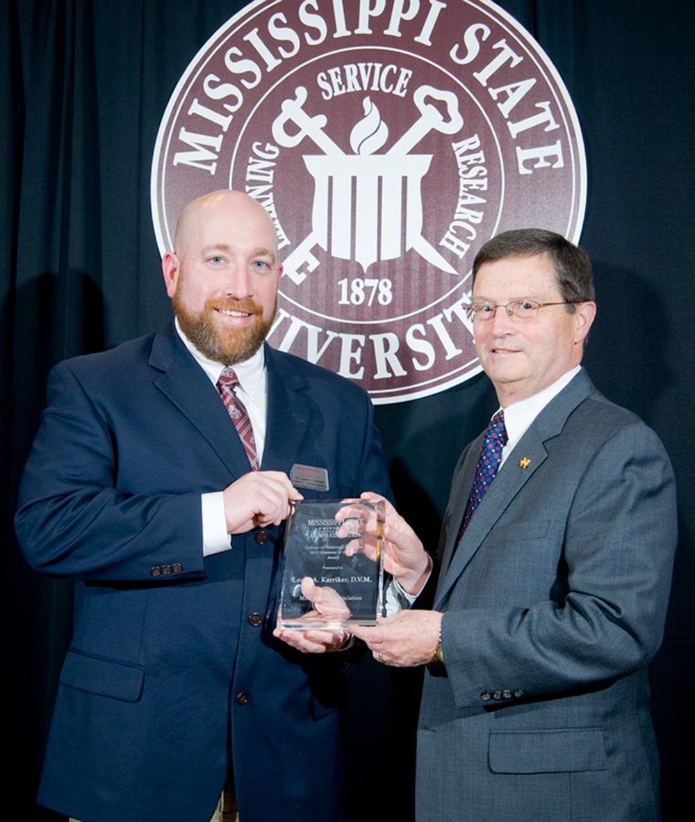 Dr. Locke Karriker, director of the Swine Medicine Education Center at Iowa State University, left, receives the 2012 College of Veterinary Medicine Alumnus of the Year award at Mississippi State University from Dr. Kent Hoblet, the college's dean. (Photo by MSU University Relations/Russ Houston)