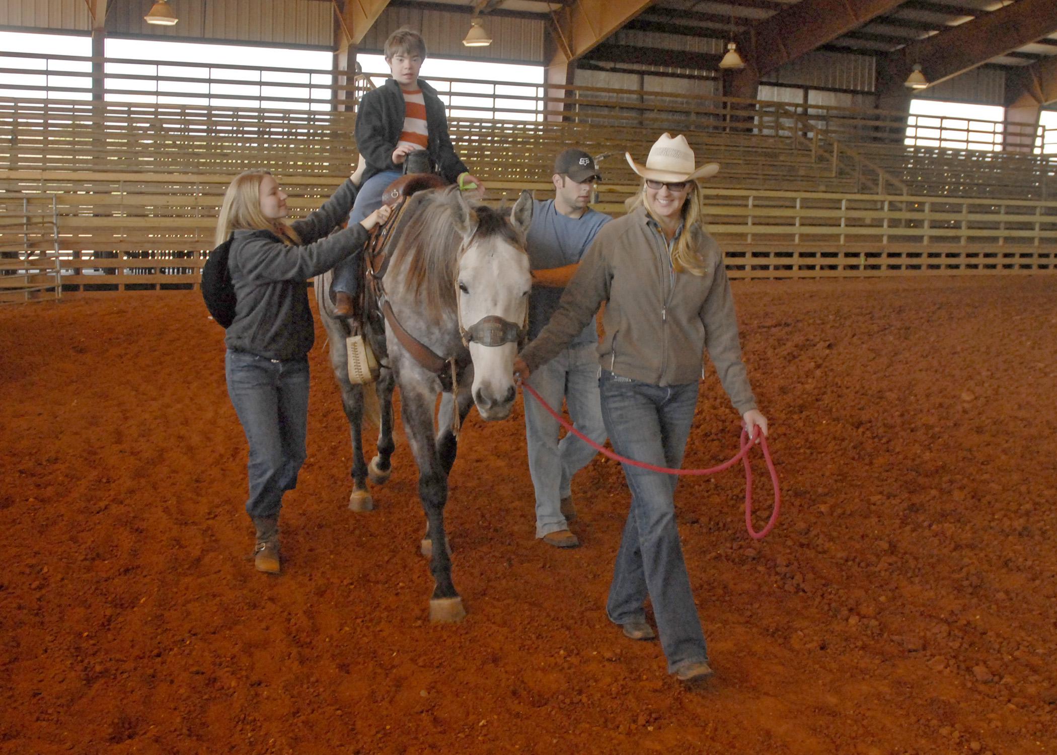 Garrett Sullivan, 10, of Laurel, enjoys a ride on Reno at the Lamar County Fairgrounds in Purvis. Turners and Burners 4-H Club volunteer leader Lona Booth, leading the horse, is assisted by side-walkers Kaitlyn Barber and Ross Mills during the Sweetheart Rodeo on March 16, 2013. (Photo by MSU Ag Communications/Linda Breazeale)
