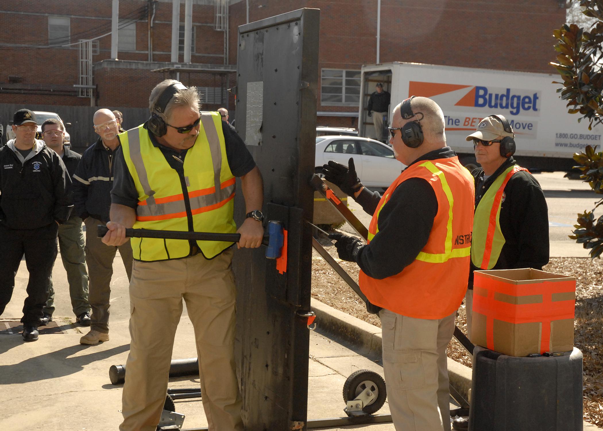 Kit Cessna, left, demonstrates one method for breaking through a door while co-instructors Joe Martel, center, and Wally Perrault assist on the Mississippi State University campus during an active-shooter response course on March 14, 2013. MSU's Extension Service coordinated the three-day course developed and facilitated by the National Center for Biomedical Research and Training, one of the leading training agencies for U.S. Department of Homeland Security initiatives. (Photo by MSU Ag Communications/Linda