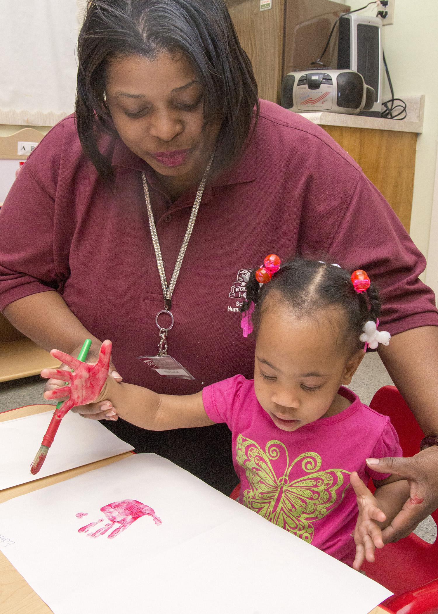 Avis Taylor, a field technical assistant with the Mississippi Child Care Resource and Referral Network, makes handprint butterflies with Eden White, 1, at West Kemper Kiddie Kollege in De Kalb.