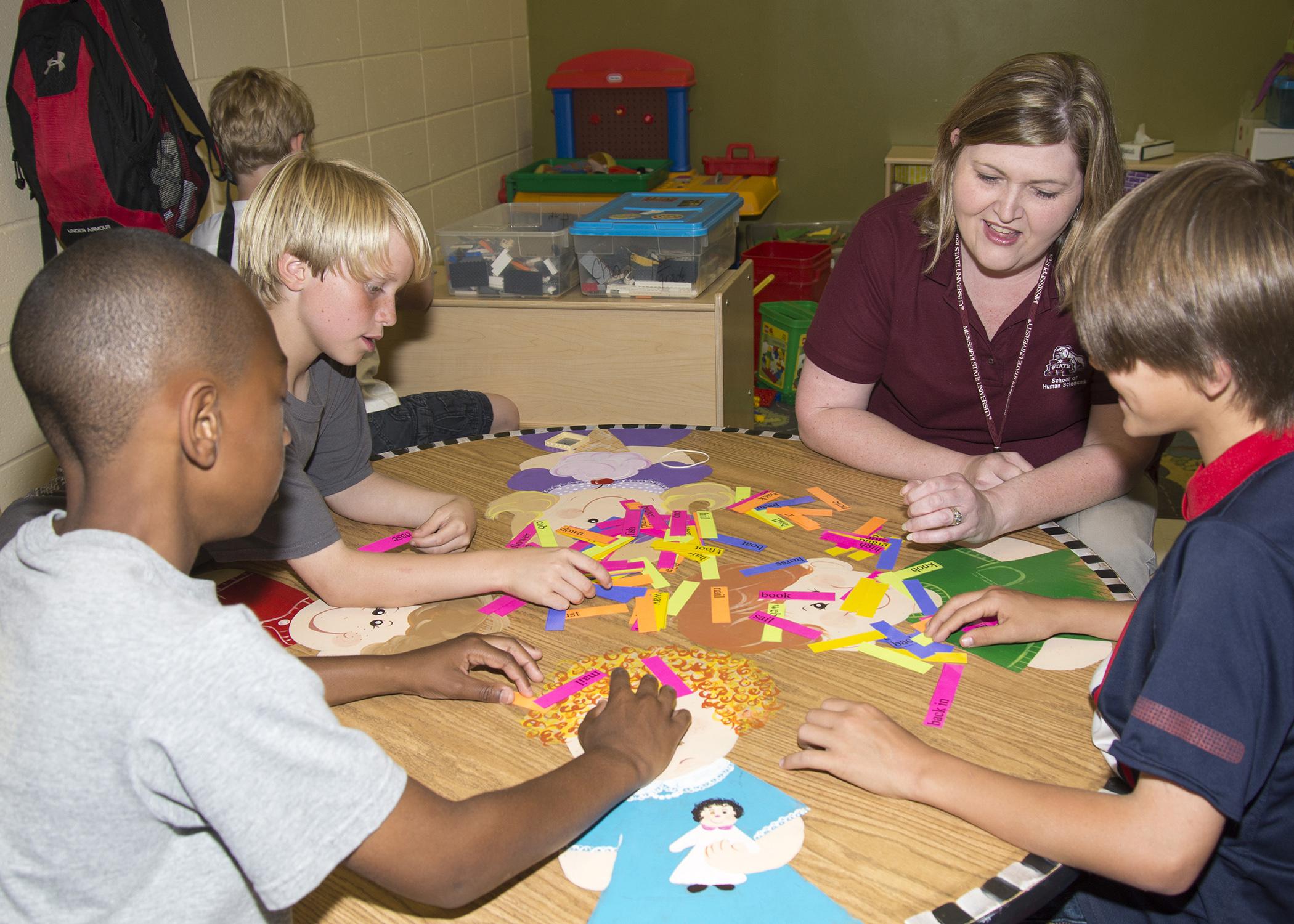 Crossgates Methodist Children's Center after-school students from left Jalen Ballard, Hardy Lewis and Layton Levingston play a compound word matching game with Tara Dickerson, a technical assistant with Mississippi State University's Out-of-School Project. (Photo by MSU School of Human Sciences/Alicia Barnes)