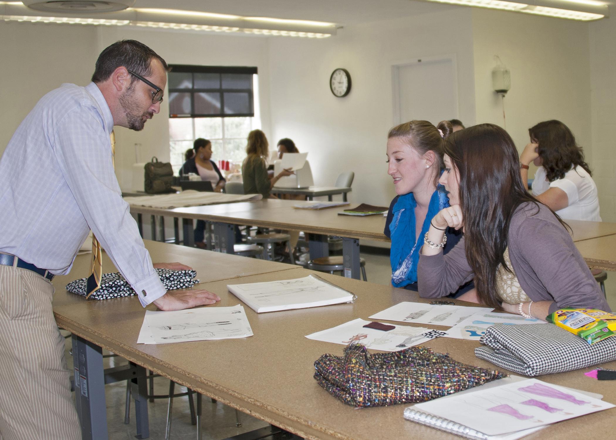 Charles Freeman, assistant professor in the Mississippi State University Apparel, Textiles and Merchandising program, looks at a sketch of a garment with Sarah Ashley Bealor, left, a senior from Tampa, and Rachel Buchanan, a senior from Pontotoc. (Photo by MSU Ag Communications/Kat Lawrence)