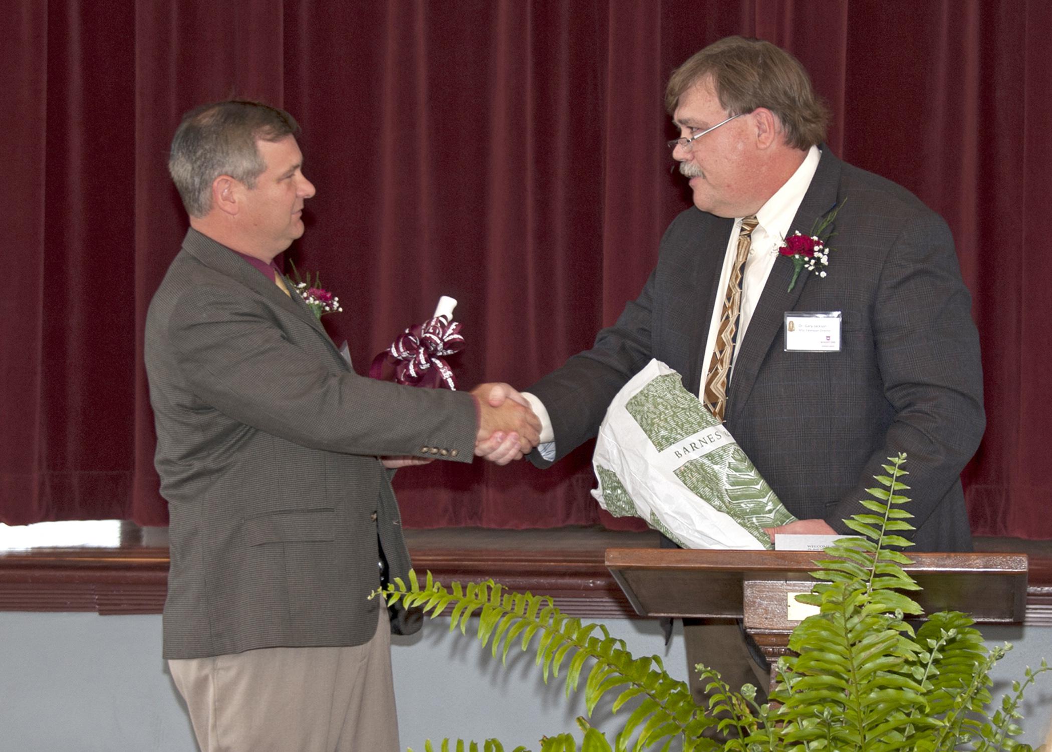 Mississippi State University Extension Service Director Gary Jackson, right, presents Forrest County Agricultural High School Superintendent Jerry Morgan with an MSU cowbell April 8, 2014, to mark the beginning of a partnership between the school and university. The Extension Service loaned the school an interactive video system that allows students, faculty and staff to attend Extension educational programs. (Photo by MSU Ag Communications/Kat Lawrence)