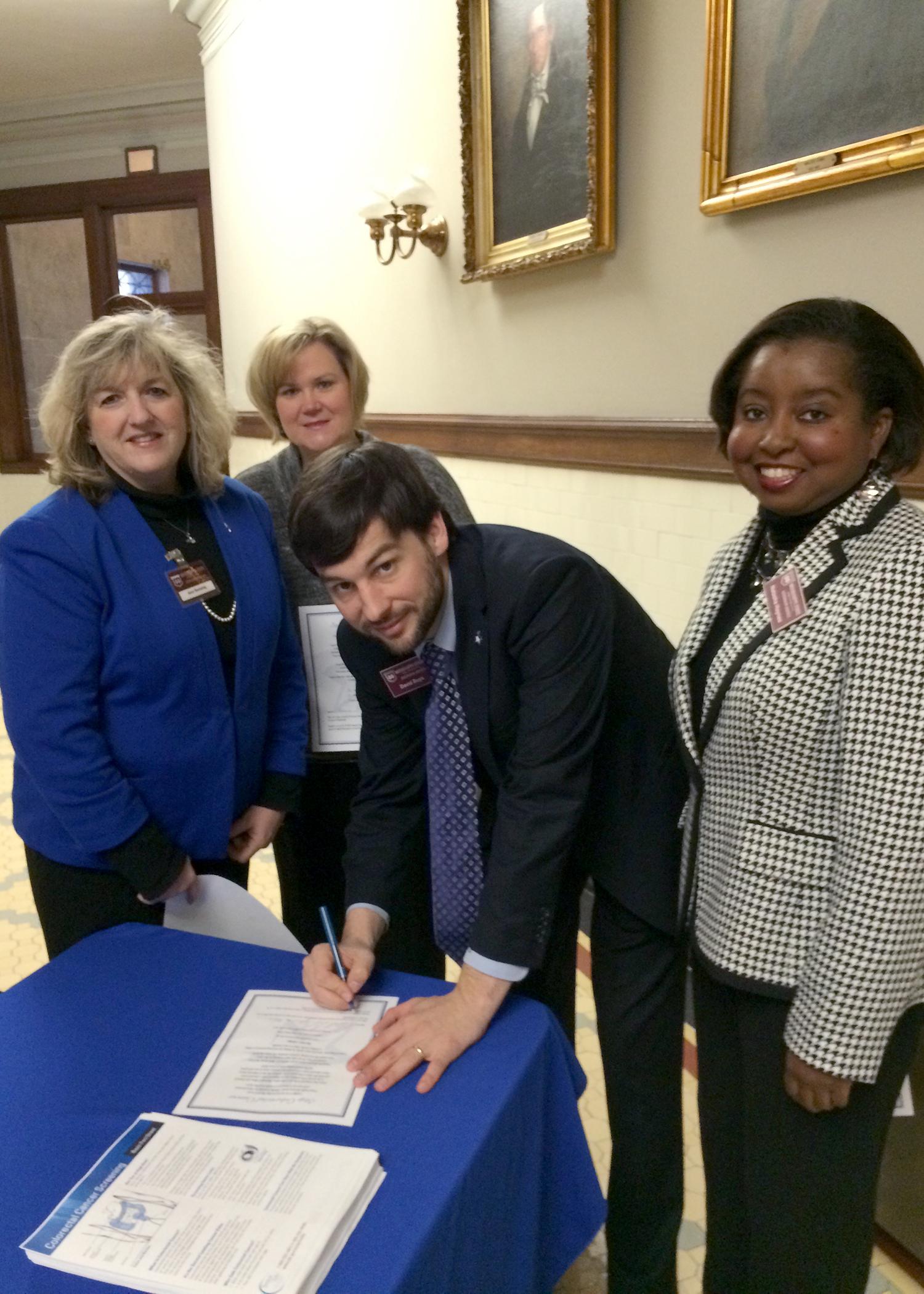 Mississippi State University Extension Service health specialist David Buys signs a pledge to be screened for colorectal cancer in 2015. Other representatives of the MSU Extension Service, Ann Sansing (from left), Theresa Hand and Natasha Haynes, are joining him in the awareness event at the Mississippi Capitol on March 9, 2015. (Submitted photo)