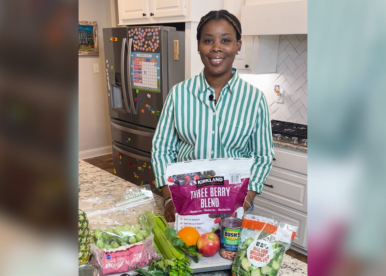 A woman stands behind a kitchen counter with a variety of foods displayed.