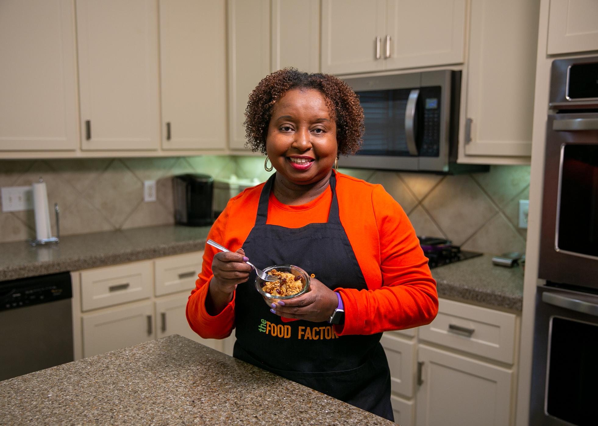 A woman stands in a kitchen and holds a bowl of Cinnamon Fried Pineapple