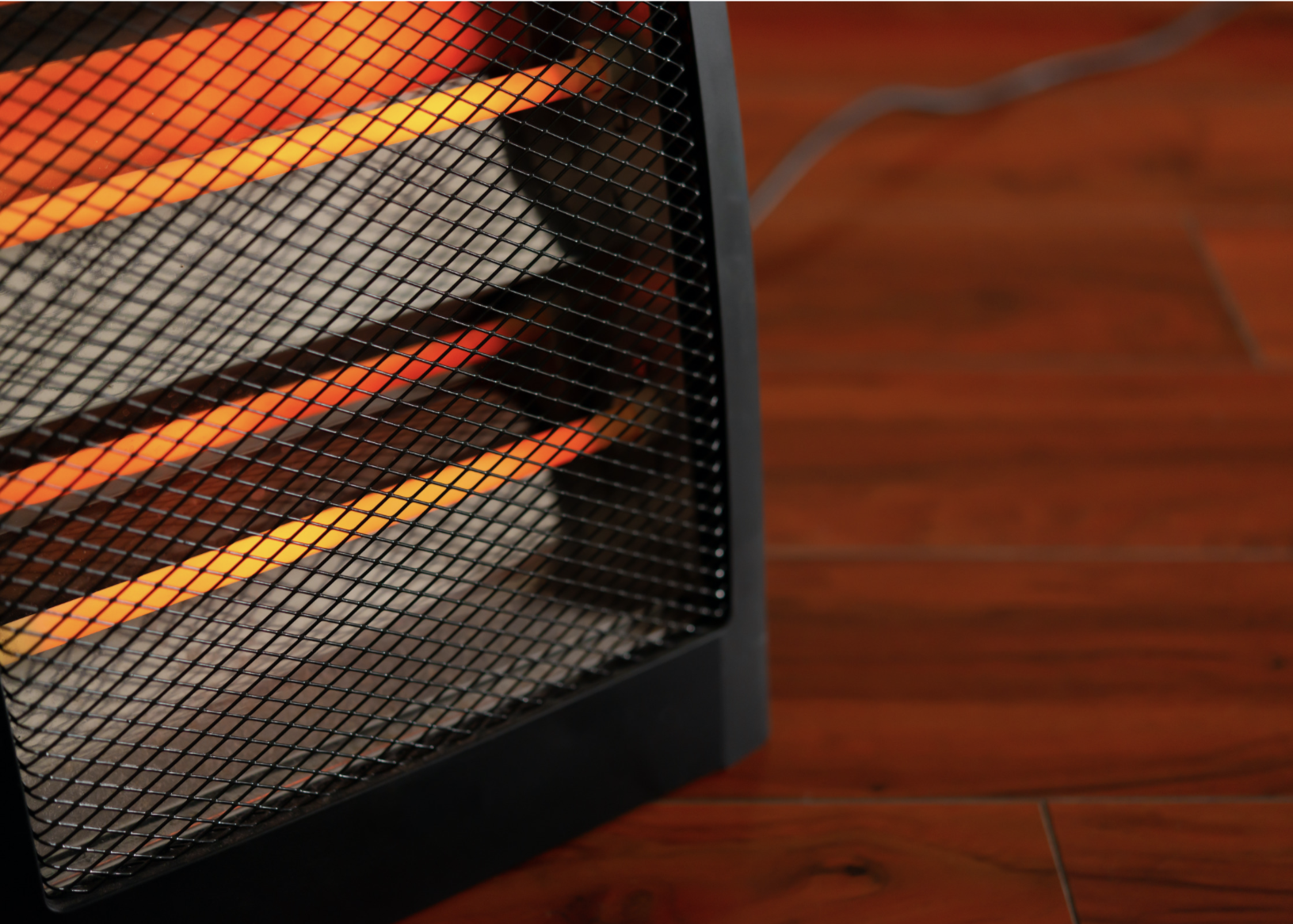 Close up of a space heater sitting on a hardwood floor