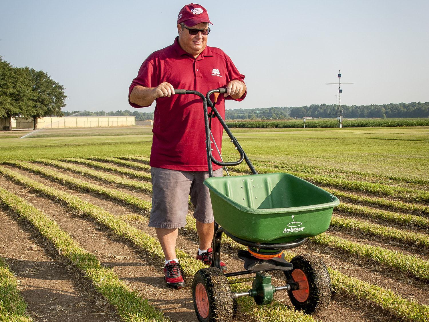 Barry Stewart, turf management specialist with the Mississippi Agricultural and Forestry Experiment Station, demonstrates fertilizing equipment on Aug. 29, 2013, on a recently cut patch of St. Augustine grass grown at Mississippi State University's R.R. Foil Research Center. (Photo by MSU Ag Communications/Scott Corey)