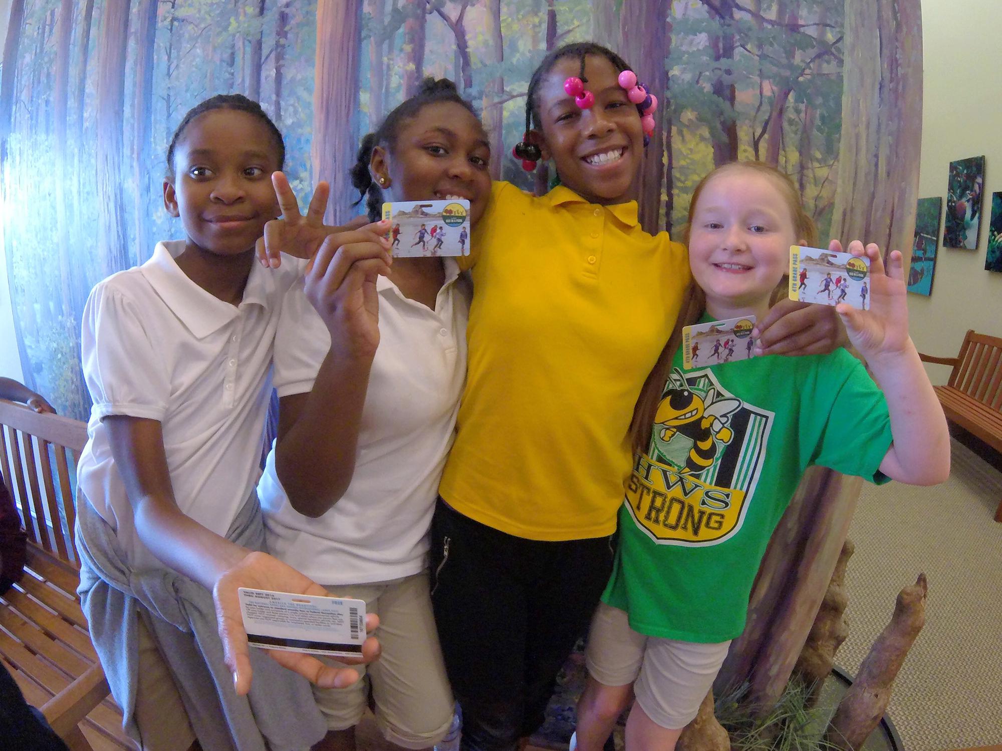 Four fourth-grade girls show off their personal identification cards that are passes to federal parks.