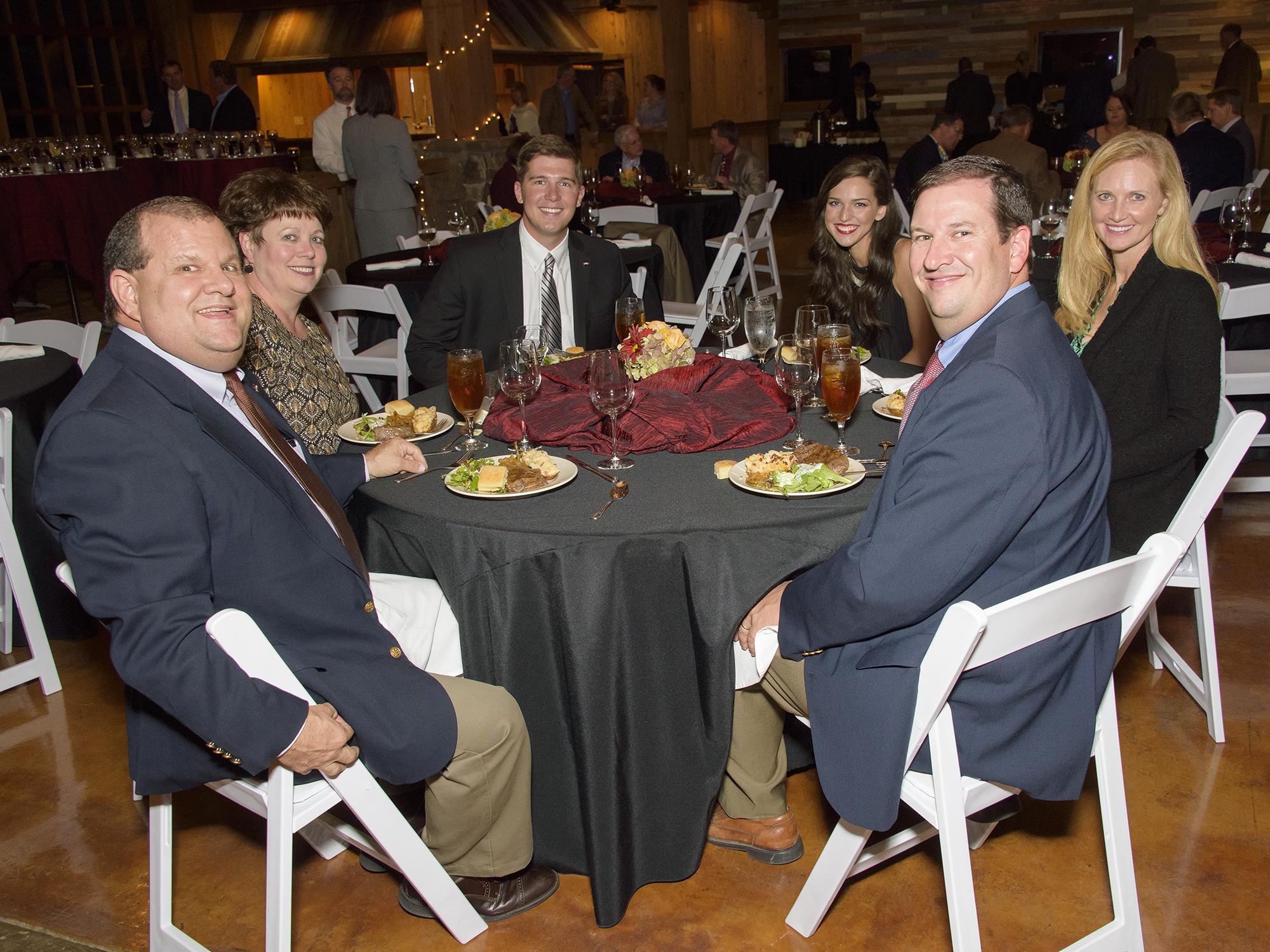 Six guests pause for a photo during a formal dinner.