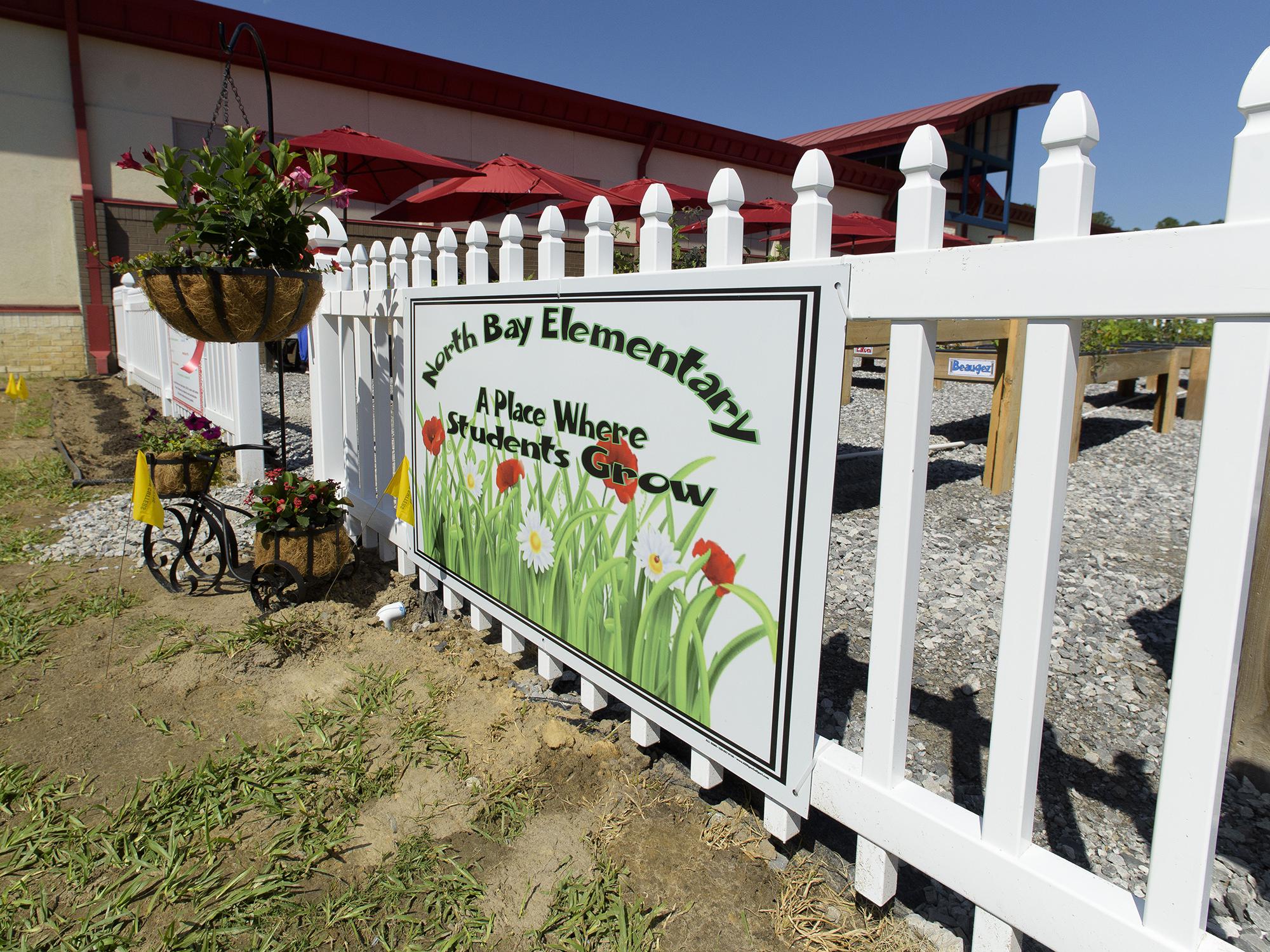 Colorful flowers are planted next to a sign at the entrance of the North Bay Elementary School garden.