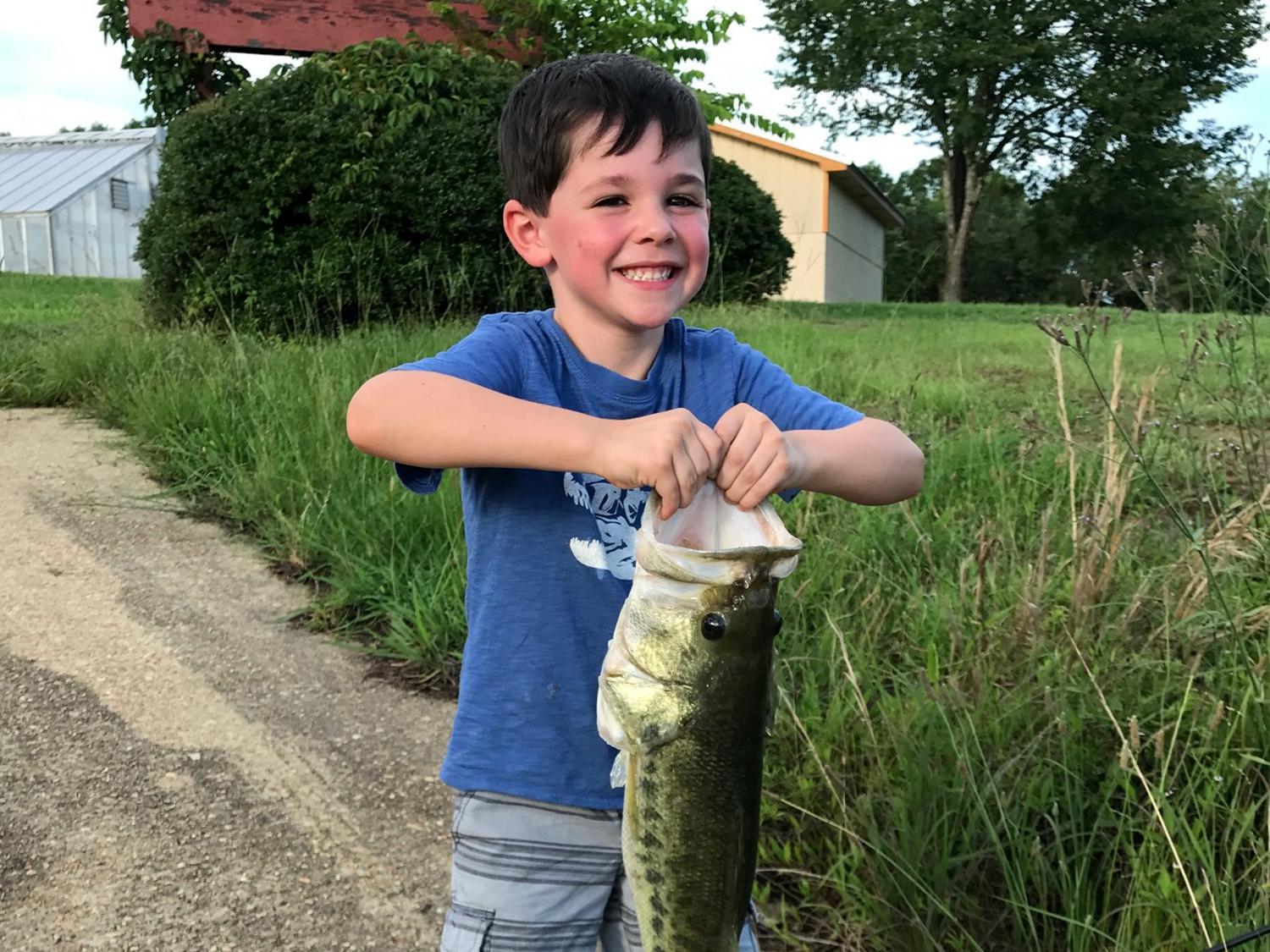 Young boy in blue shirt holding large fish.